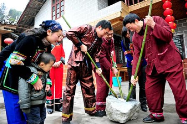 侗族风俗习惯--侗族农民冯兴超一家正在和客人一起打糍粑